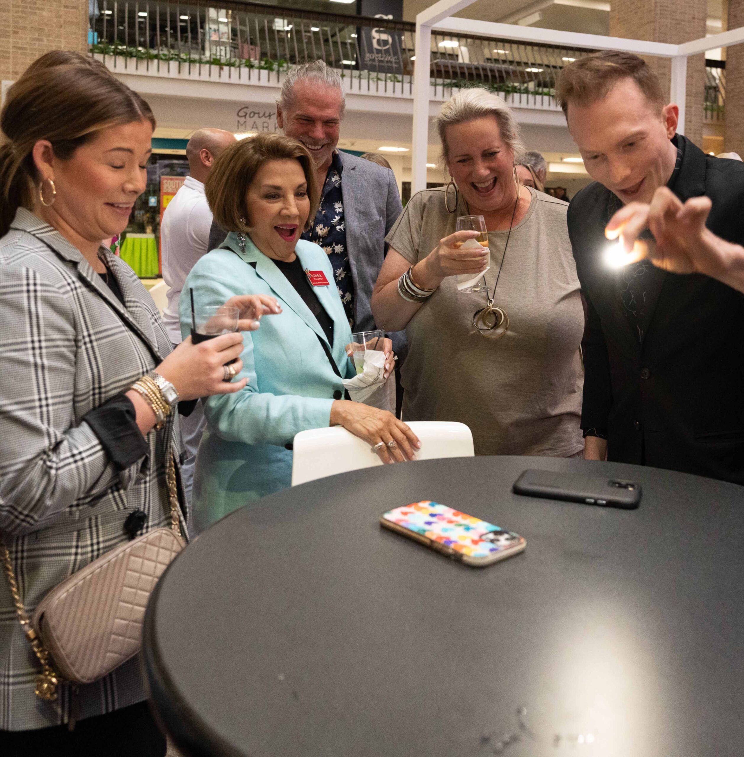 People reacting to Trigg's close-up magic at an event.