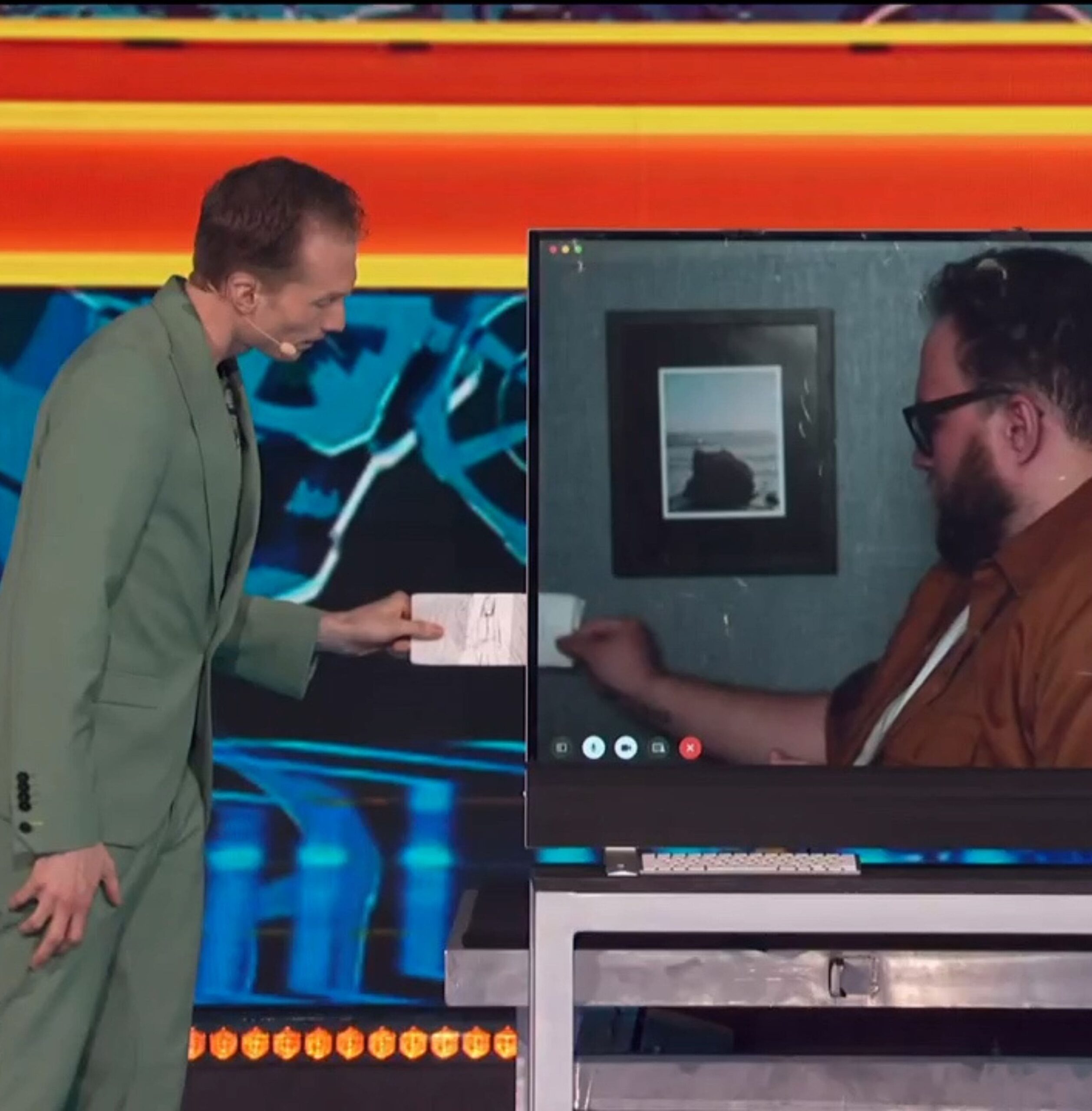 Trigg hands a hand drawing through a TV screen.