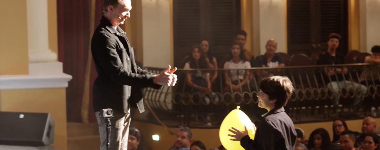 Trigg Watson performing an interactive magic trick with a young audience member on stage